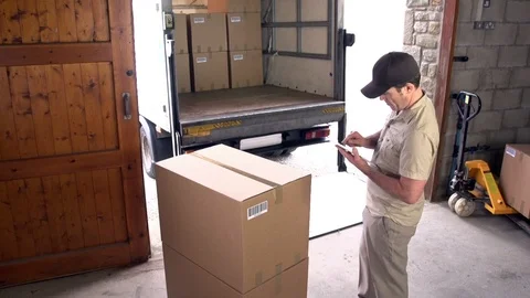 Courier / Delivery man using a Digital Tablet with parcels in the warehouse 스톡 동영상 125133171
