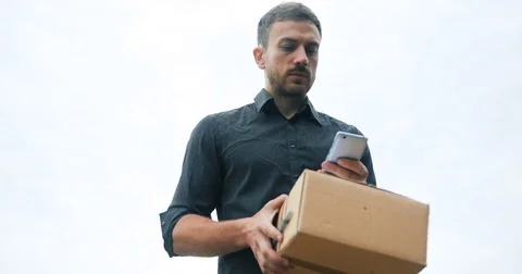 Courier delivery with parcel using mobile phone, speaking waiting for client Stock Footage 77206136