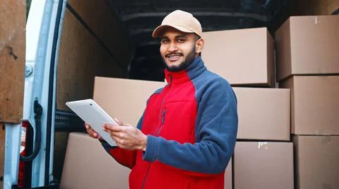 Courier with digital tablet delivering package. Mailman in front the van Stock Photos