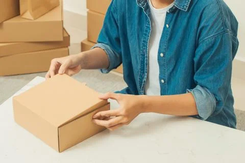 Courier hands packaging parcel at table Stock Photos