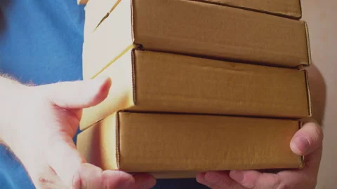 The courier is holding a stack of cardboard boxes in his hands 스톡 동영상 273502847