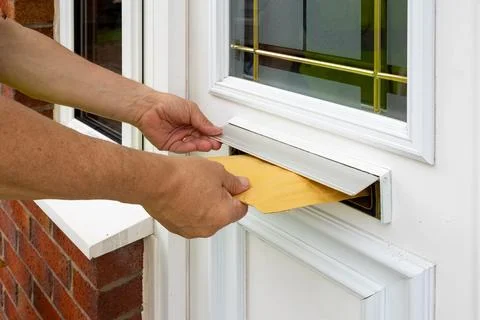 Courier Inserts Bubble Mailer Through Door Slot During Delivery Stock Photos