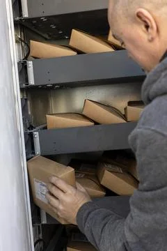 Courier loading parcels into automated delivery locker 库存照片