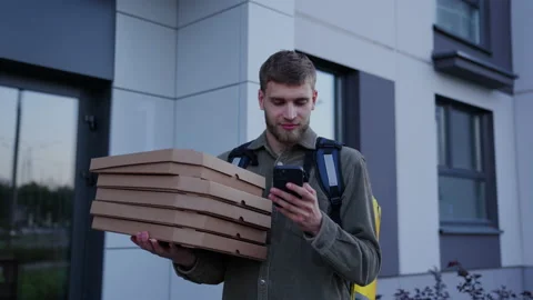 A courier man with a yellow backpack holds pizza boxes in his hands Stock Footage 205440982