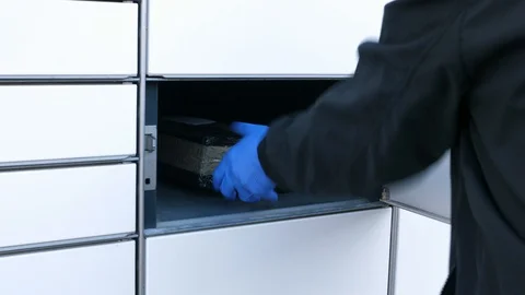 Courier in mask protective gloves placing package in box in parcel locker Stock-Footage 128879328