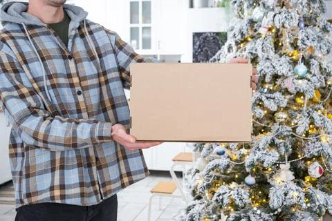 A courier with a parcel box in the kitchen with white Christmas decorations.. 写真素材