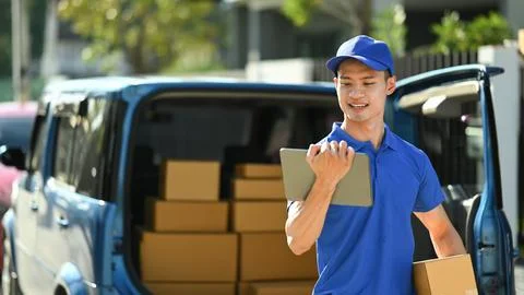 Courier with parcel standing front of the delivery service van while making home 스톡 사진