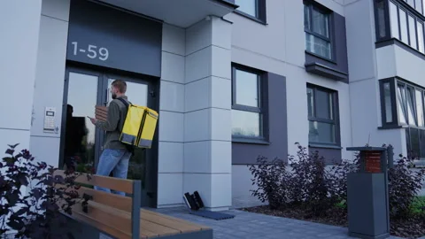 Courier with pizza boxes approaches the client's house. Ordering pizza at home Stock Footage 233978871