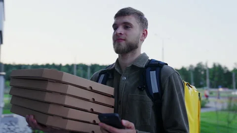 Courier with pizza boxes approaches the right entrance and rings the intercom Stock Footage 233978406