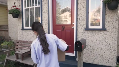 Courier placing parcel on steps at front porch Stock Footage 221041597