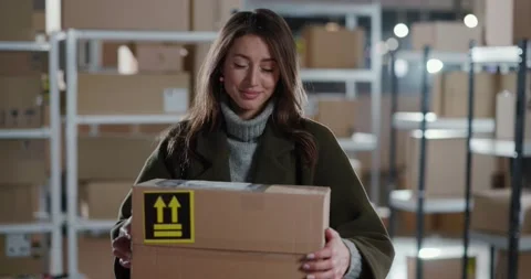 Courier in post office giving delivery parcel to female customer. Portrait of Stock Footage 150581480