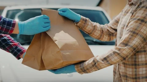 Courier in protective gloves handing over paper bags with food to customer .. Stock Footage 334593107