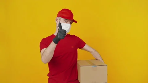 Courier in protective mask gesturing thumb up with parcel 動画素材 149623875