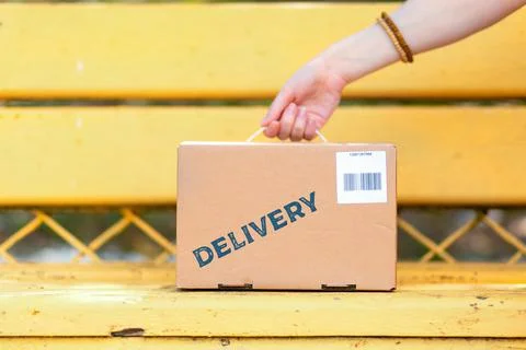 The courier puts a cardboard box with a barcode on the bench. Hand and the pa Stock Photos