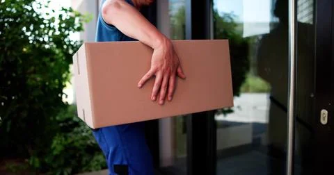 Courier Safely Delivers Package To Front Door Of Residential Home. Stock Photos