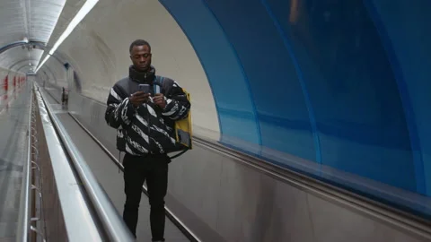 Courier service. A man with a yellow backpack and a smartphone Stock Footage 239324210