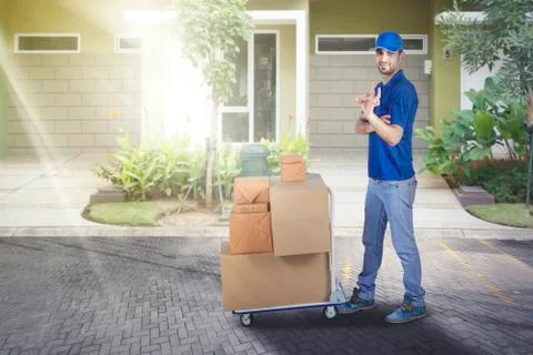 Courier showing ok gesture with stack of boxes 写真素材
