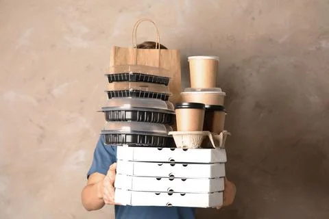 Courier with stack of orders on beige background. Food delivery service 스톡 사진