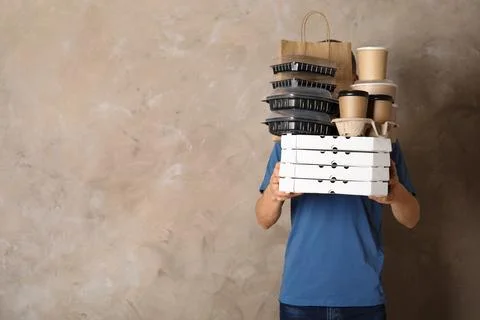 Courier with stack of orders on beige background, space for text. Food delive 스톡 사진