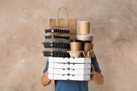 Courier with stack of orders on beige background. Food delivery service Foto stock