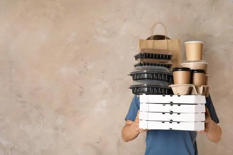 Courier with stack of orders on beige background, space for text. Food delive Stock Photos