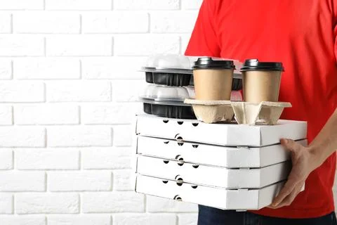 Courier with stack of orders near white brick wall, space for text. Food deli 스톡 사진