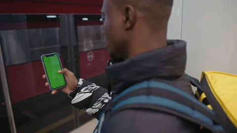 Courier stands on the platform and spends time on phone on which the chromakey Stock Footage 239323668