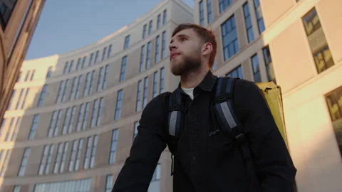 Courier stops against the background of a city block Stock Footage 243286524