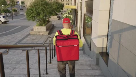 A courier takes a food order using a smartphone and walks down the street 库存影片 330995470