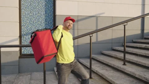 A courier takes a food order using a smartphone and walks down the street Vidéo 330995473