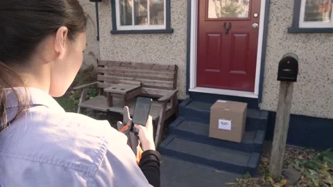Courier taking photograph of parcel on front porch Stock Footage 221041655