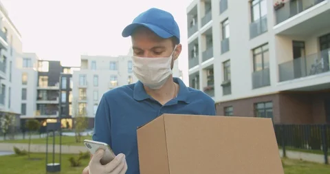 Courier tapping, texting message on smartphone outdoor and looking for address Stock Footage 129711584