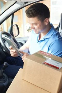 Courier In Van With Digital Tablet Delivering Package To Domestic House Stock Photos
