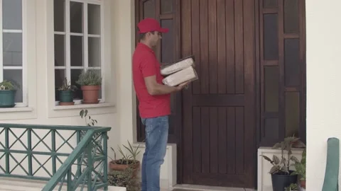 Courier wearing red cap, leaving parcels at customers door 스톡 동영상 155374275