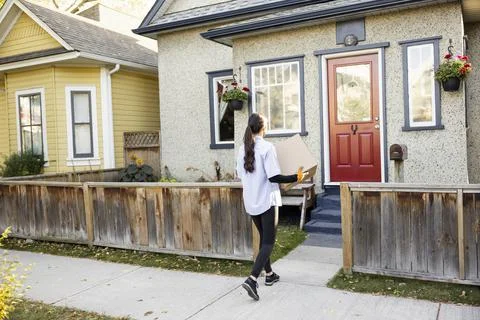 Courier worker carrying parcel to front porch Stock Photos