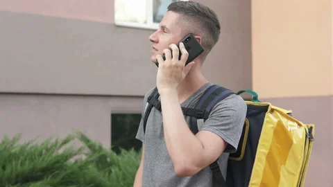 A courier with a yellow backpack delivers an online order. Stock Footage 138099080