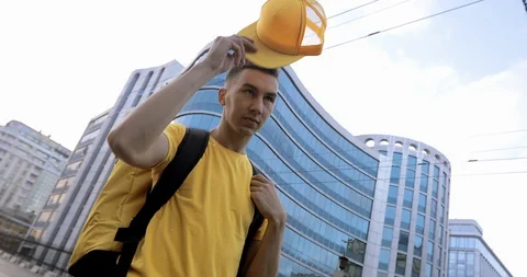 A courier in yellow clothes with a thermal backpack, business center background Stock Footage 129522490