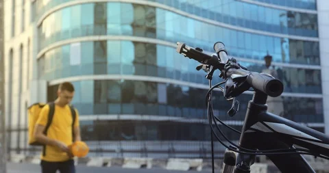 A courier in yellow clothes with a thermal backpack, business center background Video stock 129522550