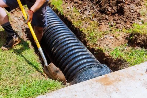 In course of construction, drainage black pipe is installed in a trench Stock Photos
