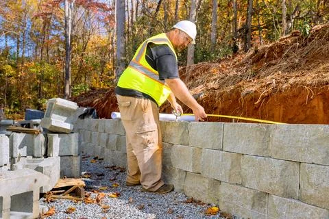 In course of mounting retaining walls by cement blocks, construction a workers 스톡 사진