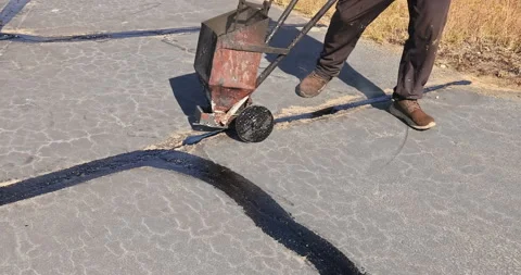 In course of worker patching patcher performs coated crack filling asphalt crack Stock Footage 260474817