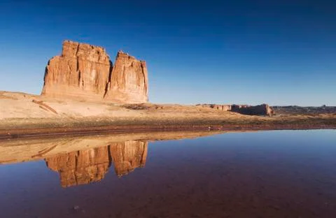 Courthouse towers at sunrise with reflection in pot hole, arches national par Stock Photos