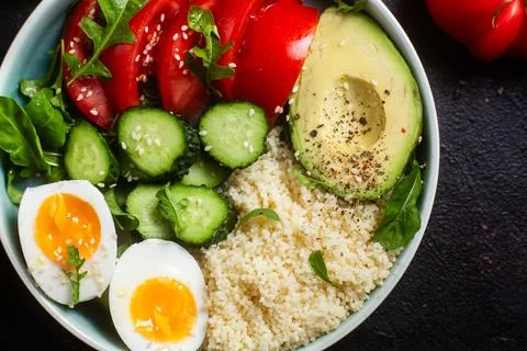 Couscous with boiled egg and vegetables in a plate on the table Stock Photos