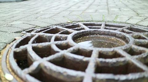 Cover the drain hatch on the road. Small ripples on the surface of the puddle. Stock Footage 68107375