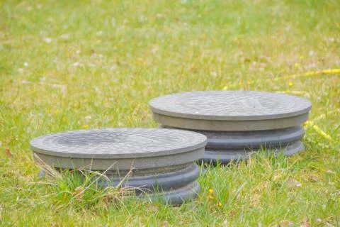 Cover sewer in the grass on the garden plot Stock Photos