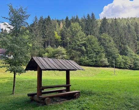 Covered bench for resting in a mountain meadow. Stock Photos