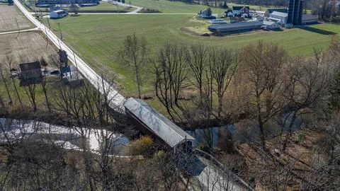 Covered Bridge Spans Tranquil Stream in Rural Landscape With Farms and Gree.. Foto stock