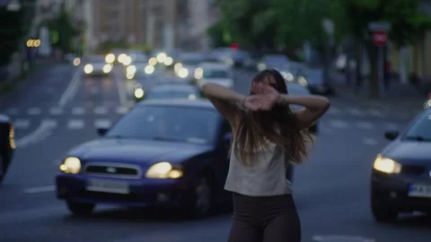 Covered by the glow of car headlights in the evening city, the girl dances. Stock Footage 246706691