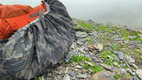 Covered hiking backpack rests on a rocky slope in dense mountain fog Stock Footage 340388932