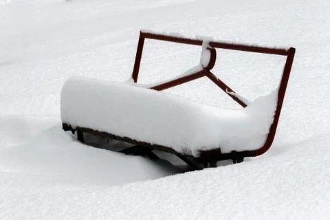 Covered with a large layer of snow bench in the city park Stock Photos